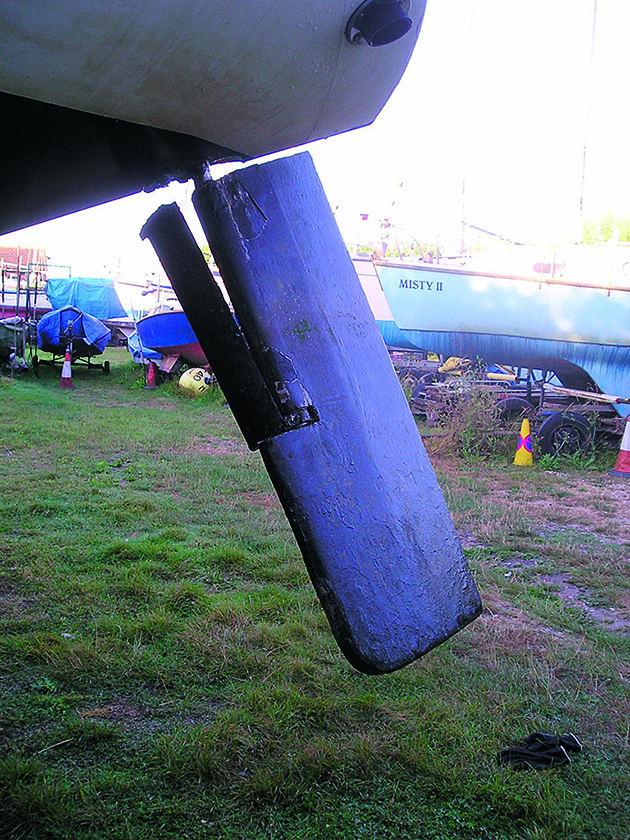 A damaged yacht rudder hanging from the hull of a boat