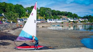 A man preparing his sailing surfboat - a topper on a beach in Scotland