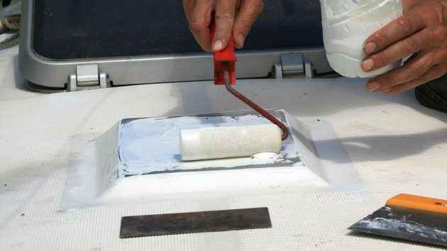 A man applying gelcoat to a boat with a roller brush