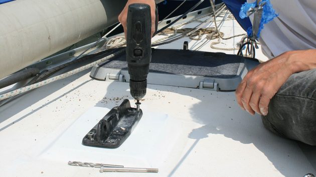 A man screwing a new mast step to the deck of a boat