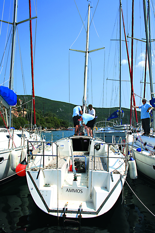 three men lowering the mast of a sailing boat