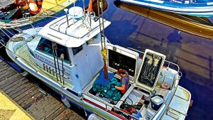 A man removing an engine from a boat which would require another boat certification in the UK