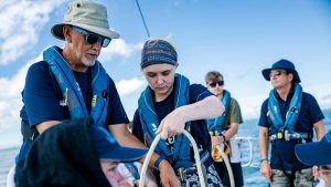 A volunteer sailor helping a child on board an Ellen MacArthur Cancer Trust boat
