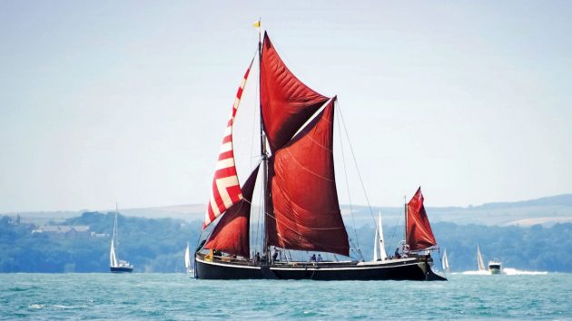 A thames sailing barge with spritsails with red sails sailing on the sea