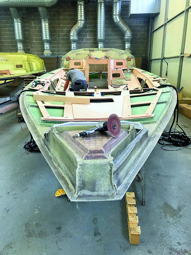 An upturned hull of a plywood boat in a factory