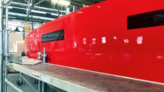 the shinning red hull of a boat in a factory