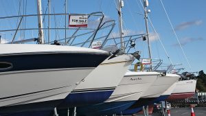 Someone looking at buying a boat wondering around boats with for sale signs on them