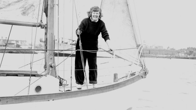 Ann Davison, wearing a black jumper and trousers standing on the deck of a boat