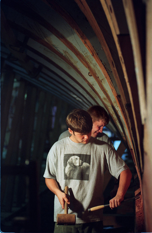 Two men working on a wooden boat