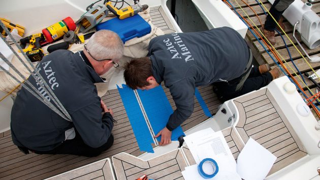 Two men measuring on a yacht ahead of tiller to wheel conversion on a boat