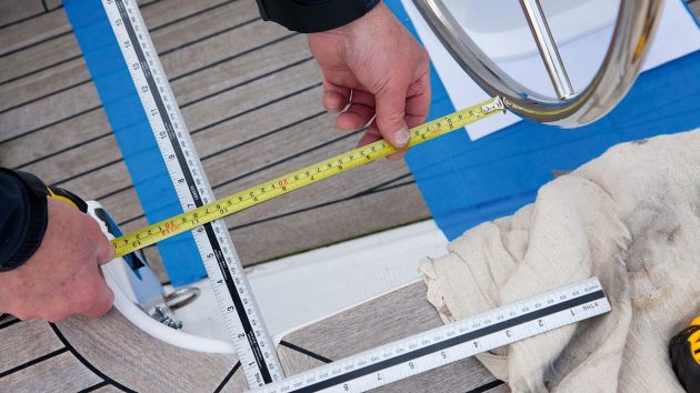 A person measuring on a yacht ahead of tiller to wheel conversion