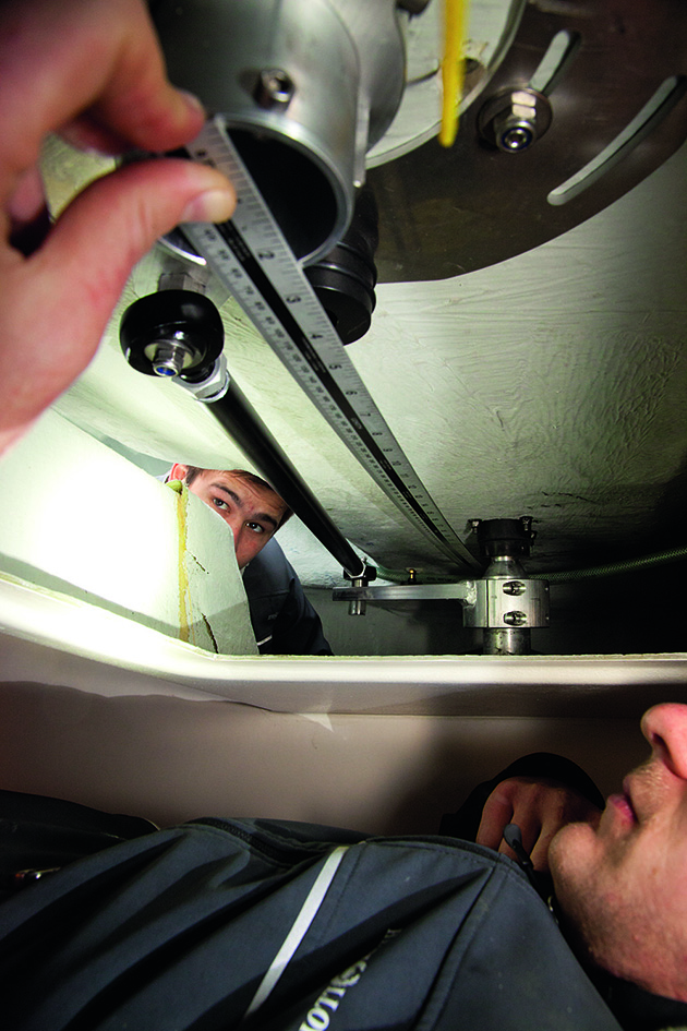 A person measuring the drag link on a wheel pedestal on a yacht