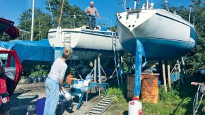 A man and a woman in a boatyard working on a boat