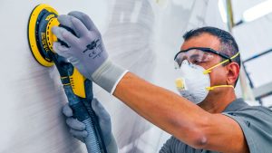 A man wearing PPE while polishing the hull of a boat