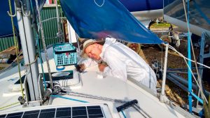 A man in white overalls working on a yacht