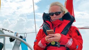 A woman looking at the What's Ashore app on her phone while sitting on a boat
