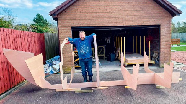 A man holding the frames of a motorboat in his garage