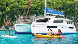 People kayaking around a catamaran boat while on a charter holiday