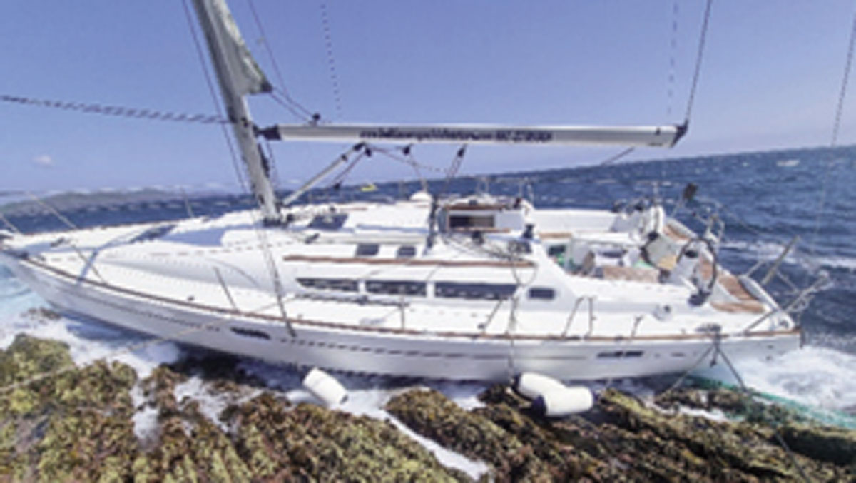 A yacht on the rocks with a discarded green trawl net wrapped around the propeller