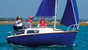 A Voyager yacht being sailed by a man and two girls