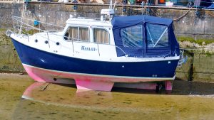 A motorboat drying out by a wall as the tide goes out