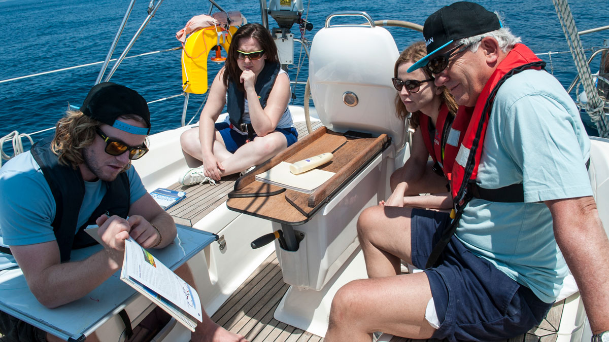 A boat skipper showing a passage plan to the crew on a boat
