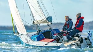 Two men wearing lifejackets sailing a Pointer 22 boat with yellow sails