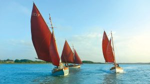 Three Deben Cherub boats sailing with their red sails raised