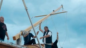 A mast hinged on a tabernacle being raised by men
