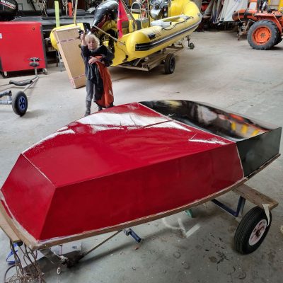 A six year old boy painting his Optimist dinghy Spiderman colours