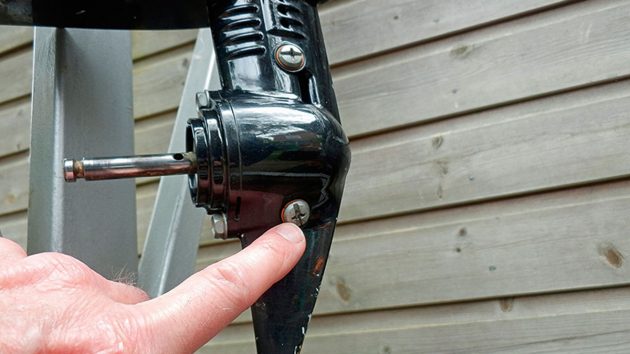 A man finding a gear oil drain plug as part of outboard motor gearbox rebuild