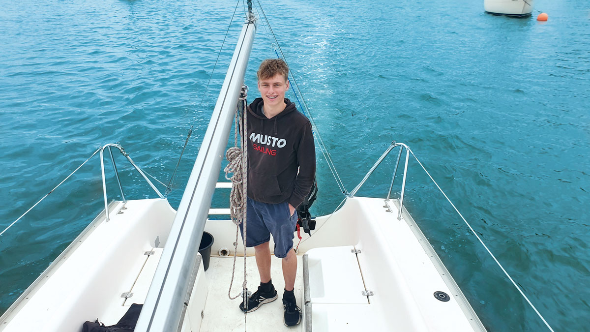 A teenager standing on the back of a Jeanneau Sun 2000 boat