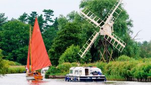 A boat passing a windmill on the UK inland boating network