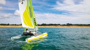 Two people sailing an IZIBoat catamaran off the coast of France