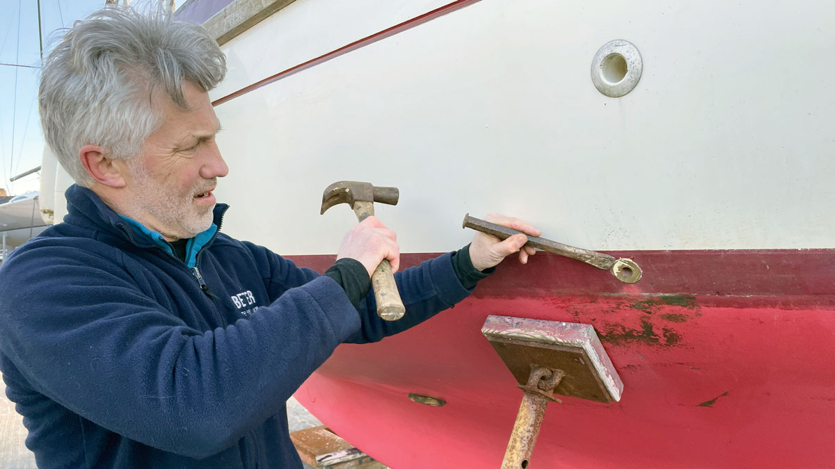 A man removing through-hull fittings from a boat