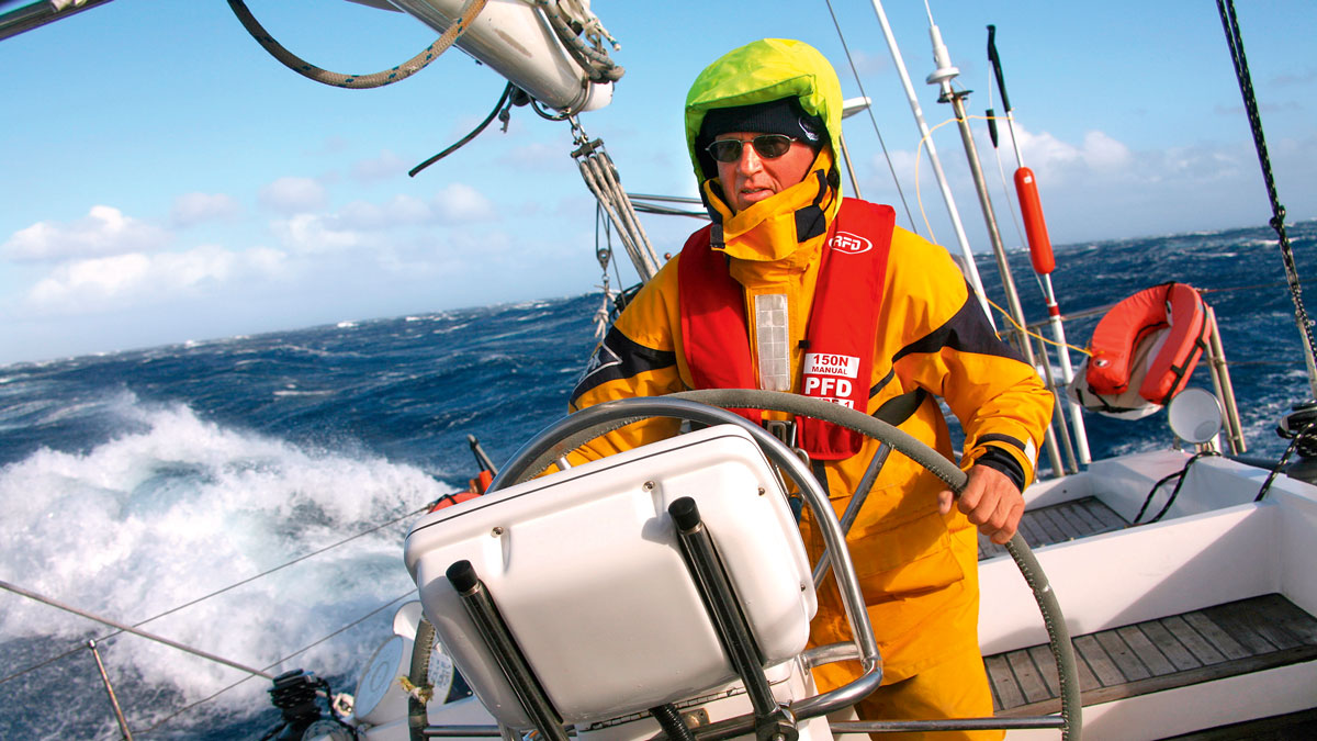 A man at the helm of the boat while heavy weather sailing