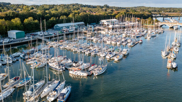 An aerial of boats moored in a marina on a river