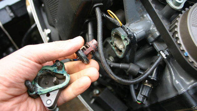 A man working on an engine ahead of backflushing the outboard