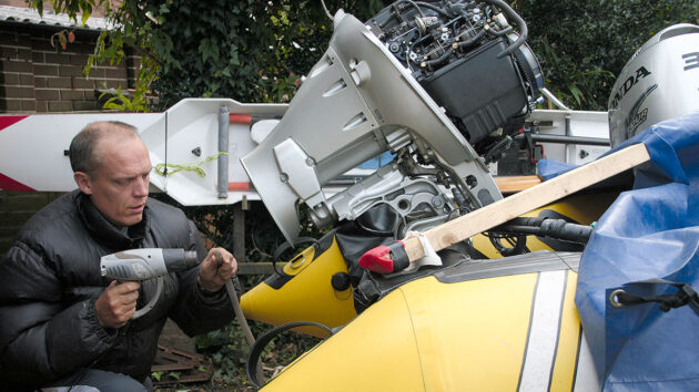 A man working ahead of backflushing an outboard