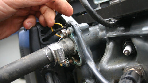 A man working on an engine before backflushing the outboard