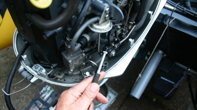 A man working on an engine ahead of backflushing an outboard