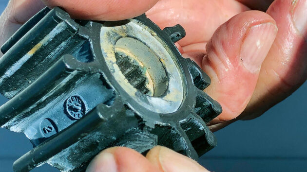 A man checking a water pump impeller on a boat engine