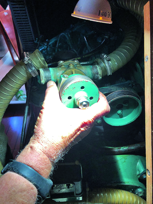 A man removing a water pump from a boat engine