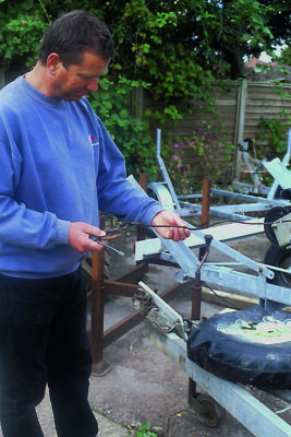 A man looking over a used boat trailer