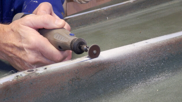 A person using a Dremel to clean a hull