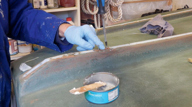 A man screwing packing piece in a hull of a boat