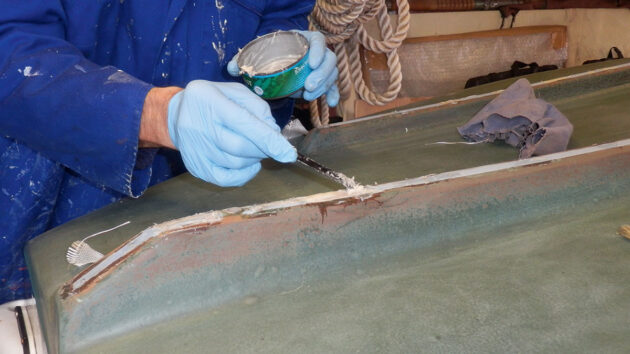 A man filling in holes on a boat