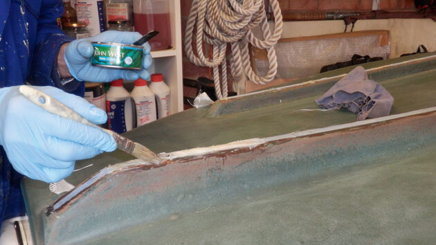 A man epoxying a boat having removed the keel band and made repairs