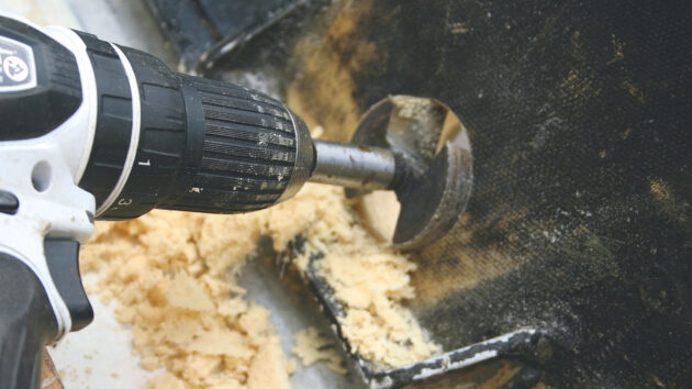 A drill being used to cut a hole in a boat