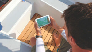 A man looking at a mobile phone at sailing apps on a boat